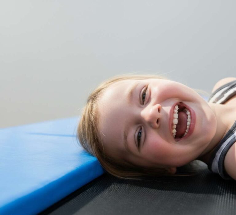 kind die lacht en op een trampoline ligt in een binnenspeeltuin