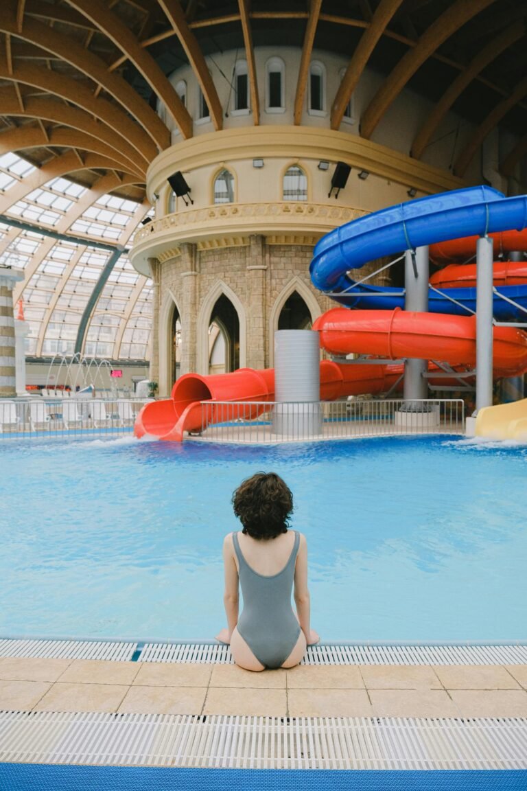 Subtropisch binnenzwembad met grote rode en blauwe glijbanen onder glazen koepel