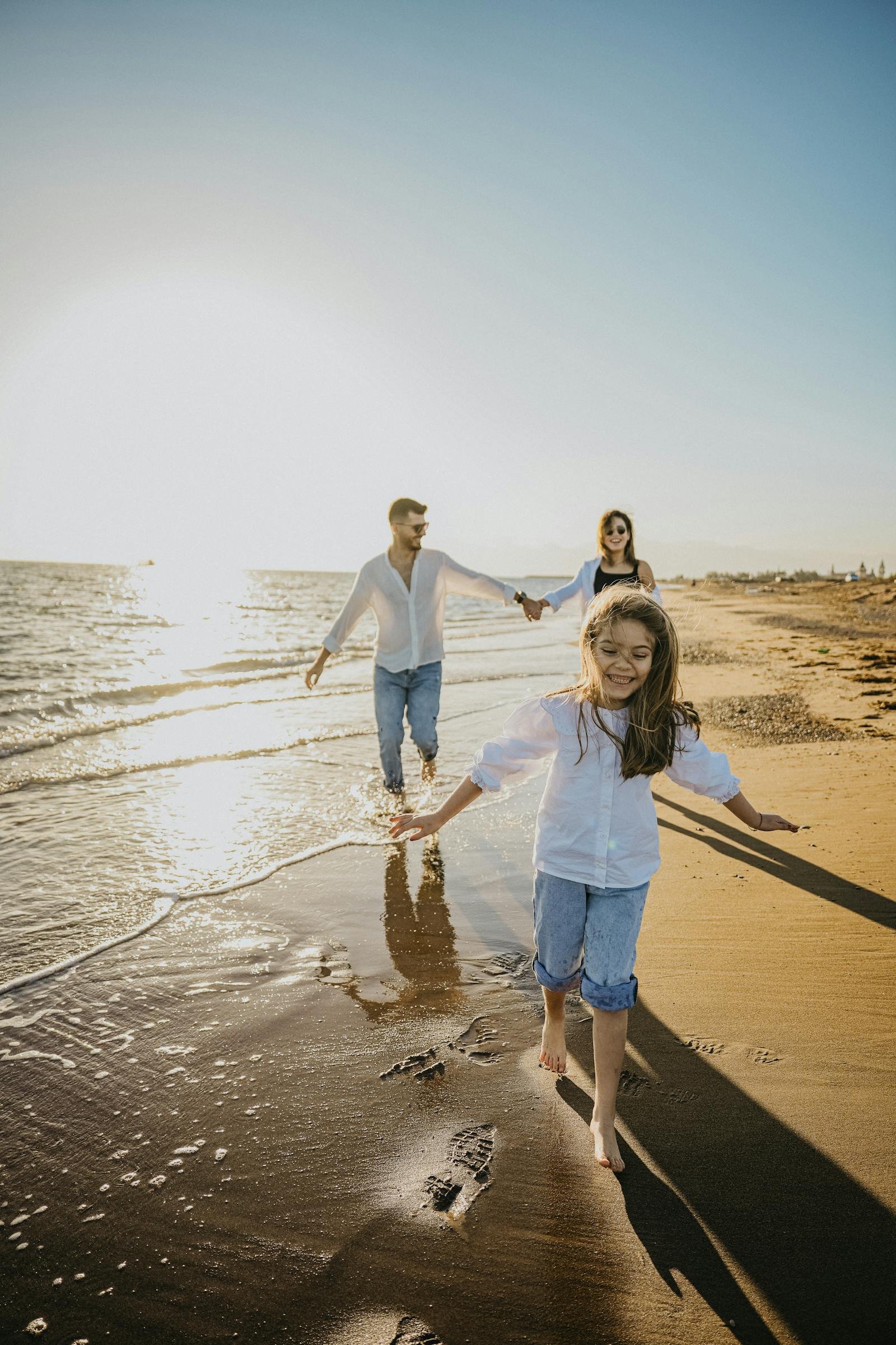Gezin wandelend over een Nederlands strand bij zonsondergang - vakantie met AH Roompot voucher