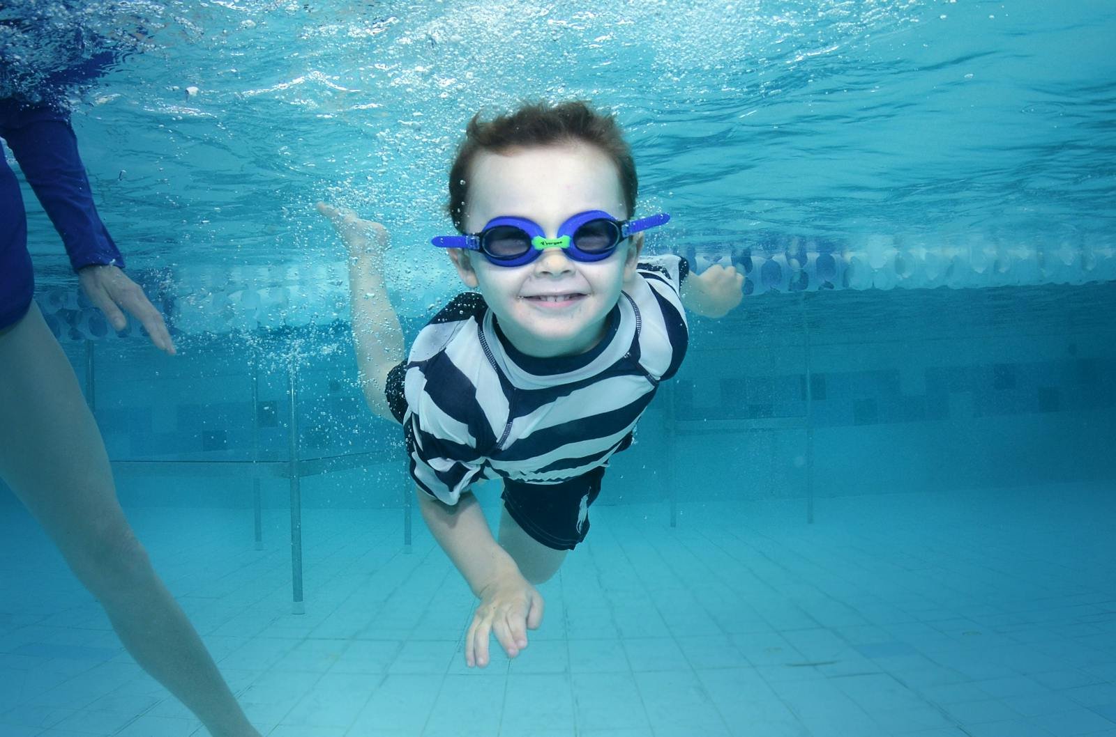 Kind onderwater met blauwe zwembril in Aqua Mundo zwembad