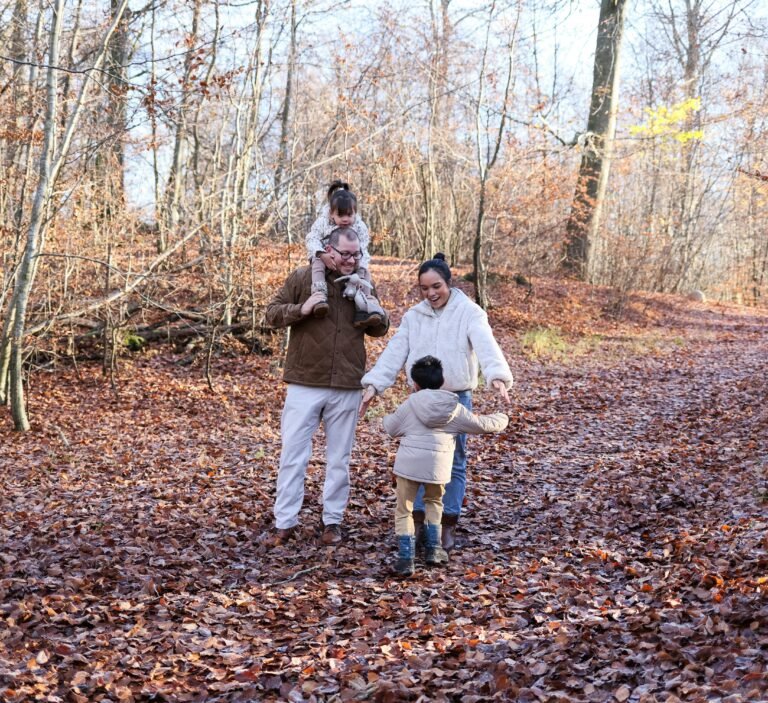 Gezin met twee kinderen wandelt door herfstbos - kindvriendelijke parken in Belgie
