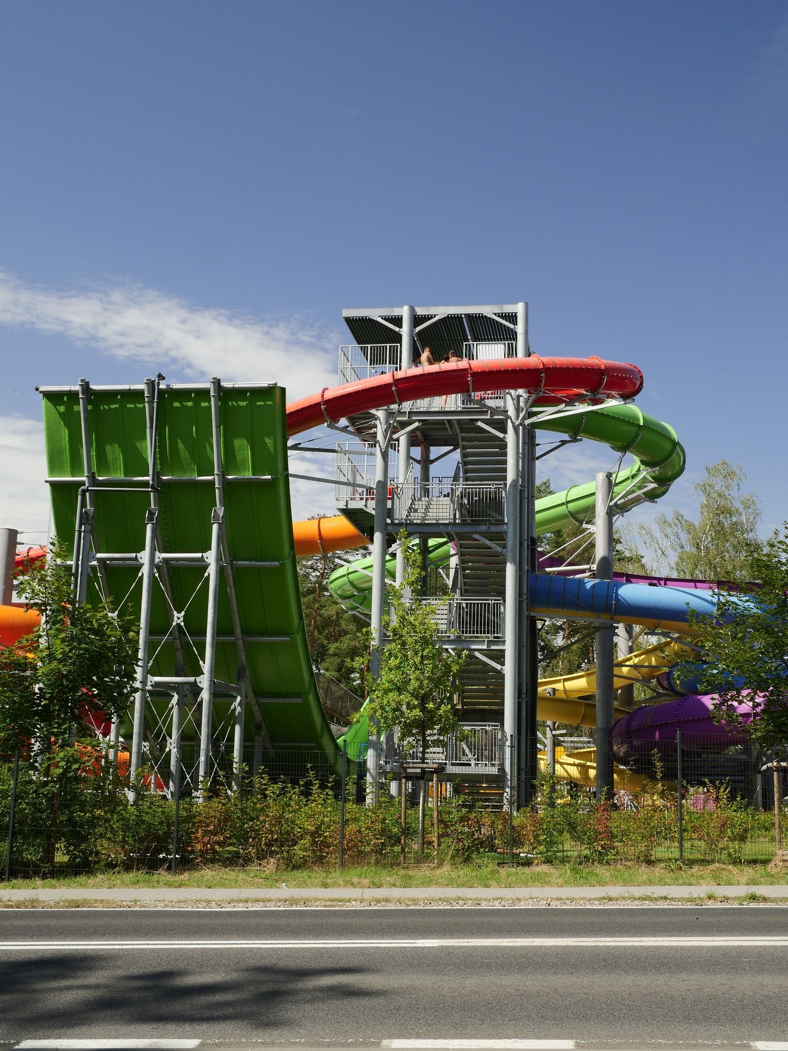 Kleurrijk waterglijbanen-park in Europa, met meerdere kleurige glijbanen onder blauwe lucht