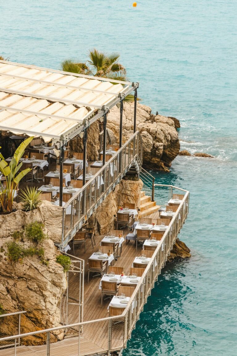 Restaurant terras met zicht op zee bij zonsondergang, parasols en gasten dineren