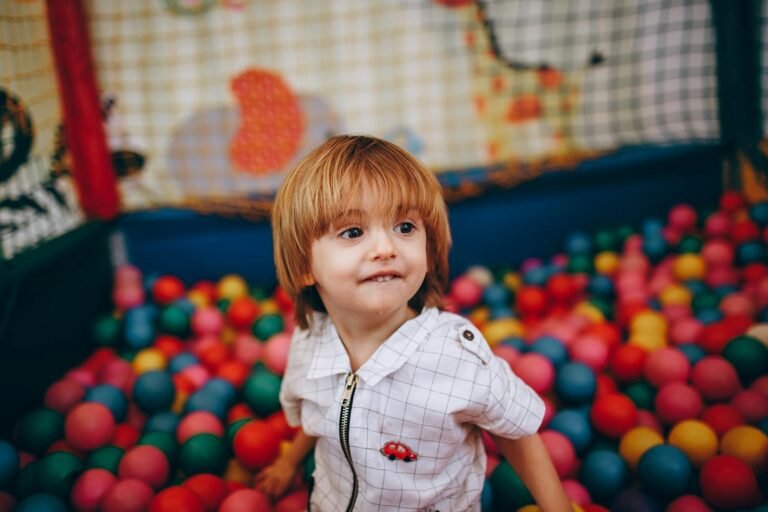 Kind speelt enthousiast in een kleurrijke ballenbak in een indoor speeltuin