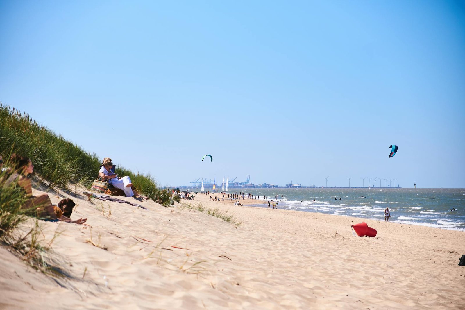 Zonnige dag op een Noordzeestrand met kitesurfers in de verte