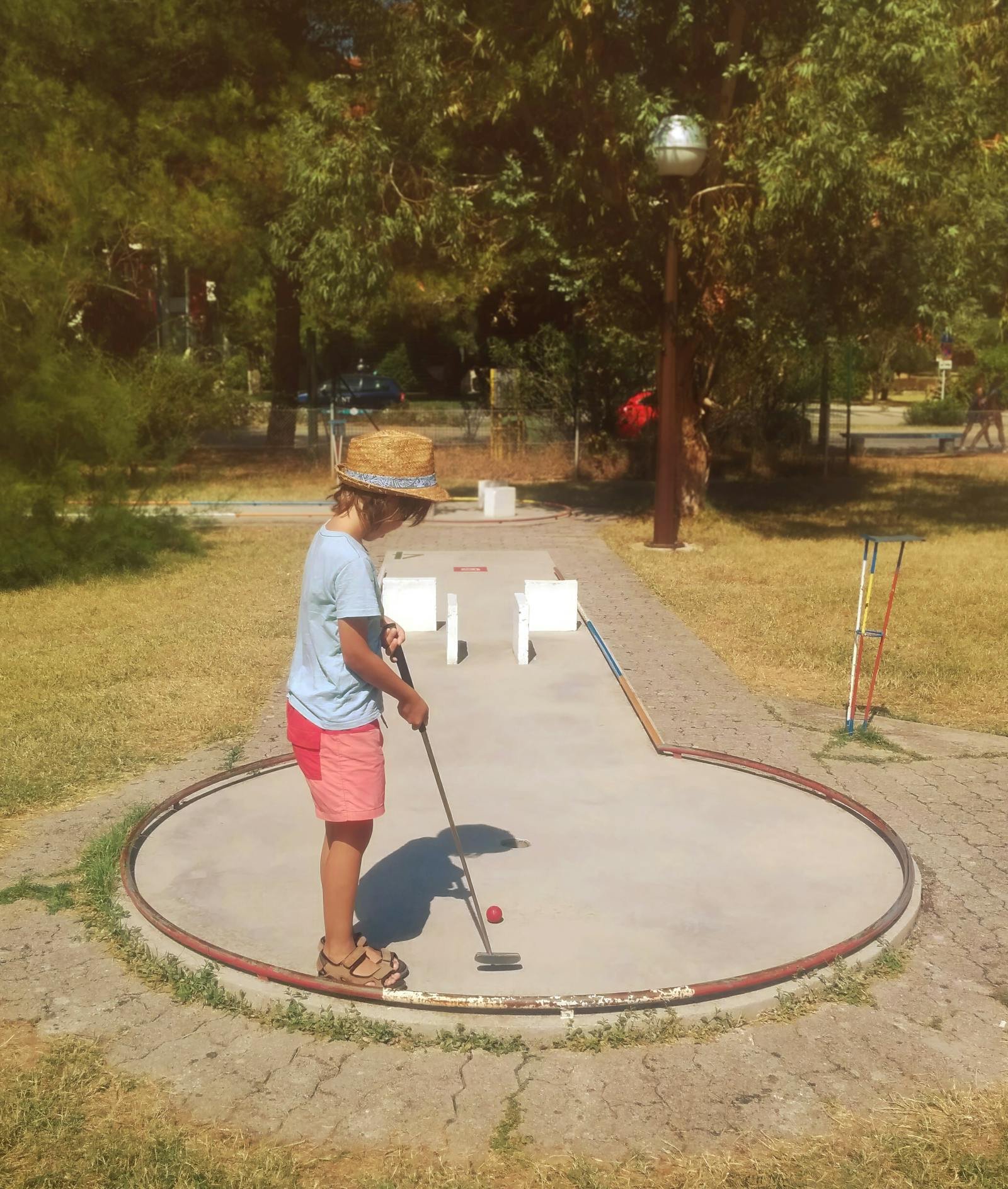 Kind speelt minigolf op een vakantiepark met groene kunstgrasbaan