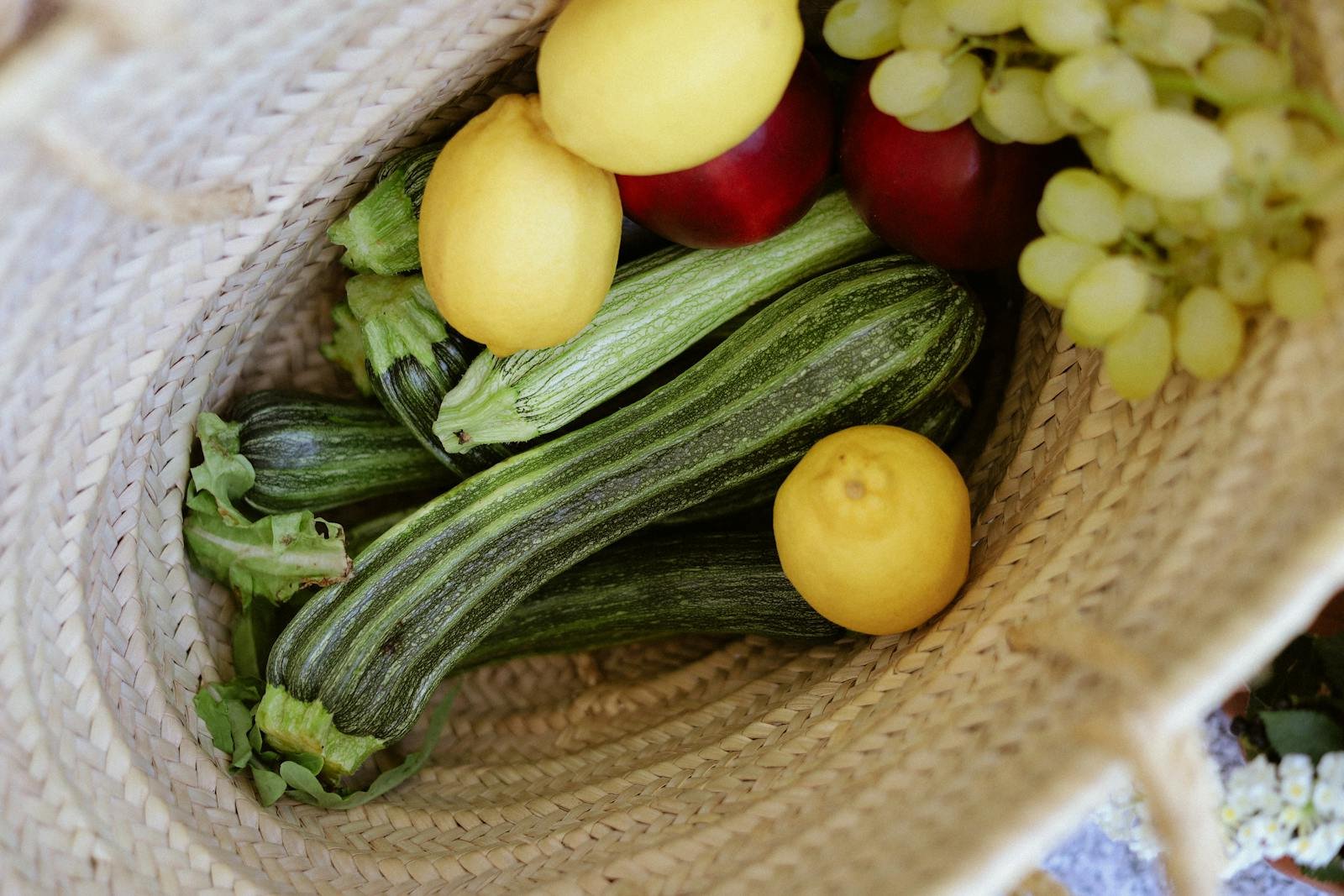 Mandje met verse groenten en fruit (courgette, citroenen, appels, druiven)