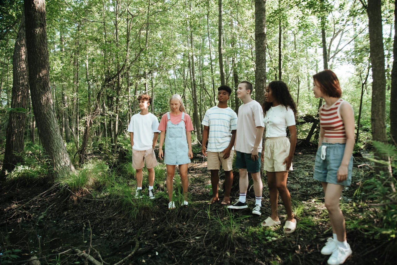 Groep tieners in een loofbos zoals je dat in de Belgische Ardennen tegenkomt