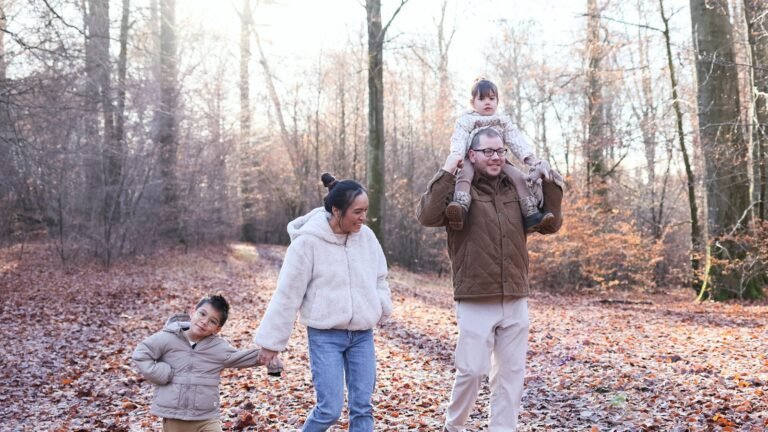 Gezin met twee kinderen wandelt door zonnig loofbos — sfeer van de Ardennen rond Center Parcs Les Ardennes