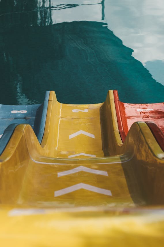 Kinderen op een gele waterglijbaan in een vakantiepark met zwembad