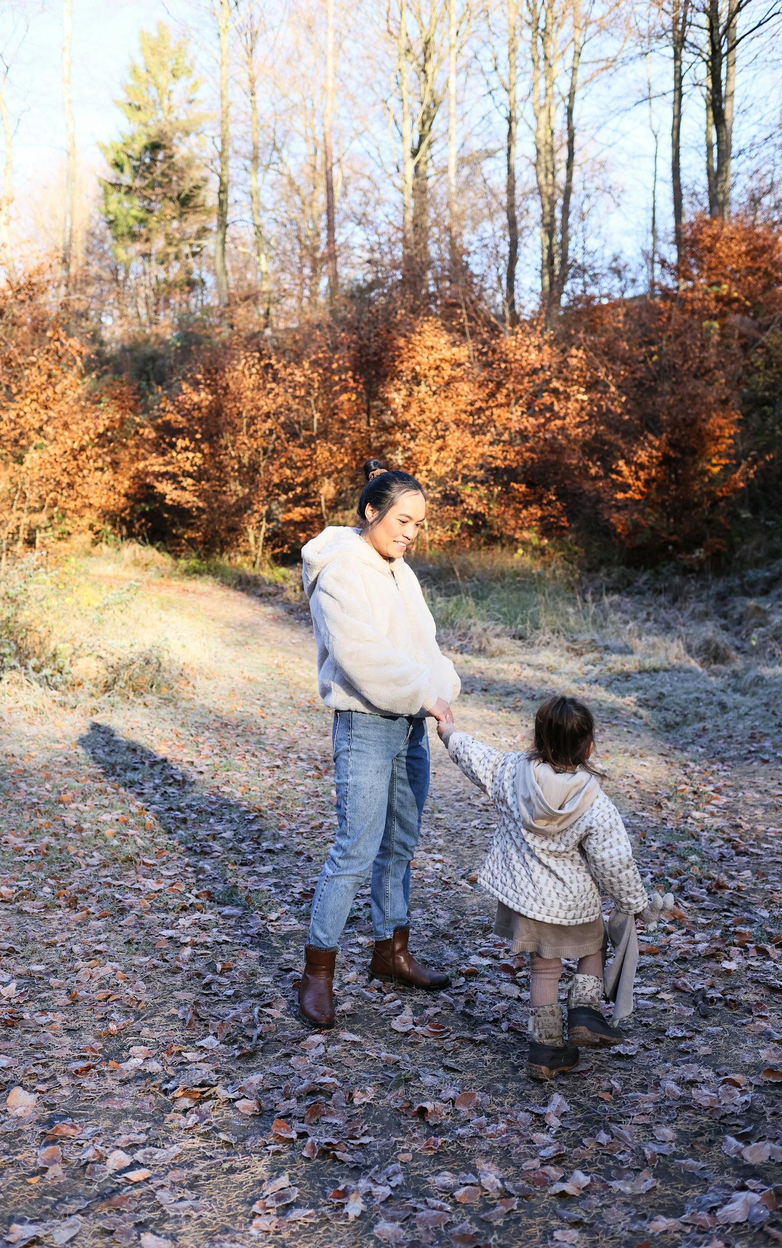 Moeder en kind wandelen door zonnig herfstbos - vakantieparken in Nederland