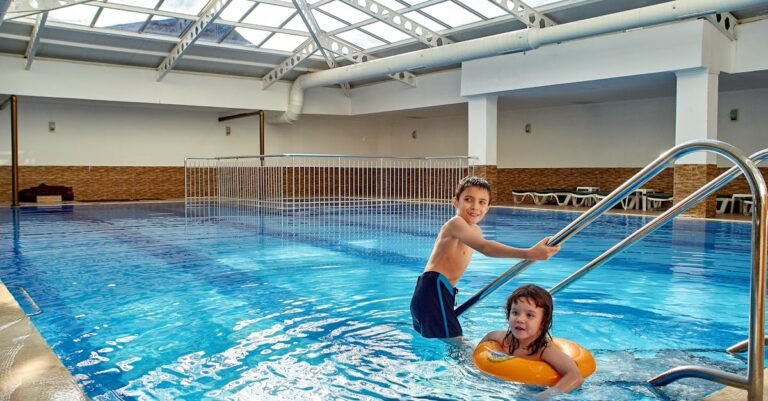 Twee kinderen spelen in een binnenzwembad met glazen dak