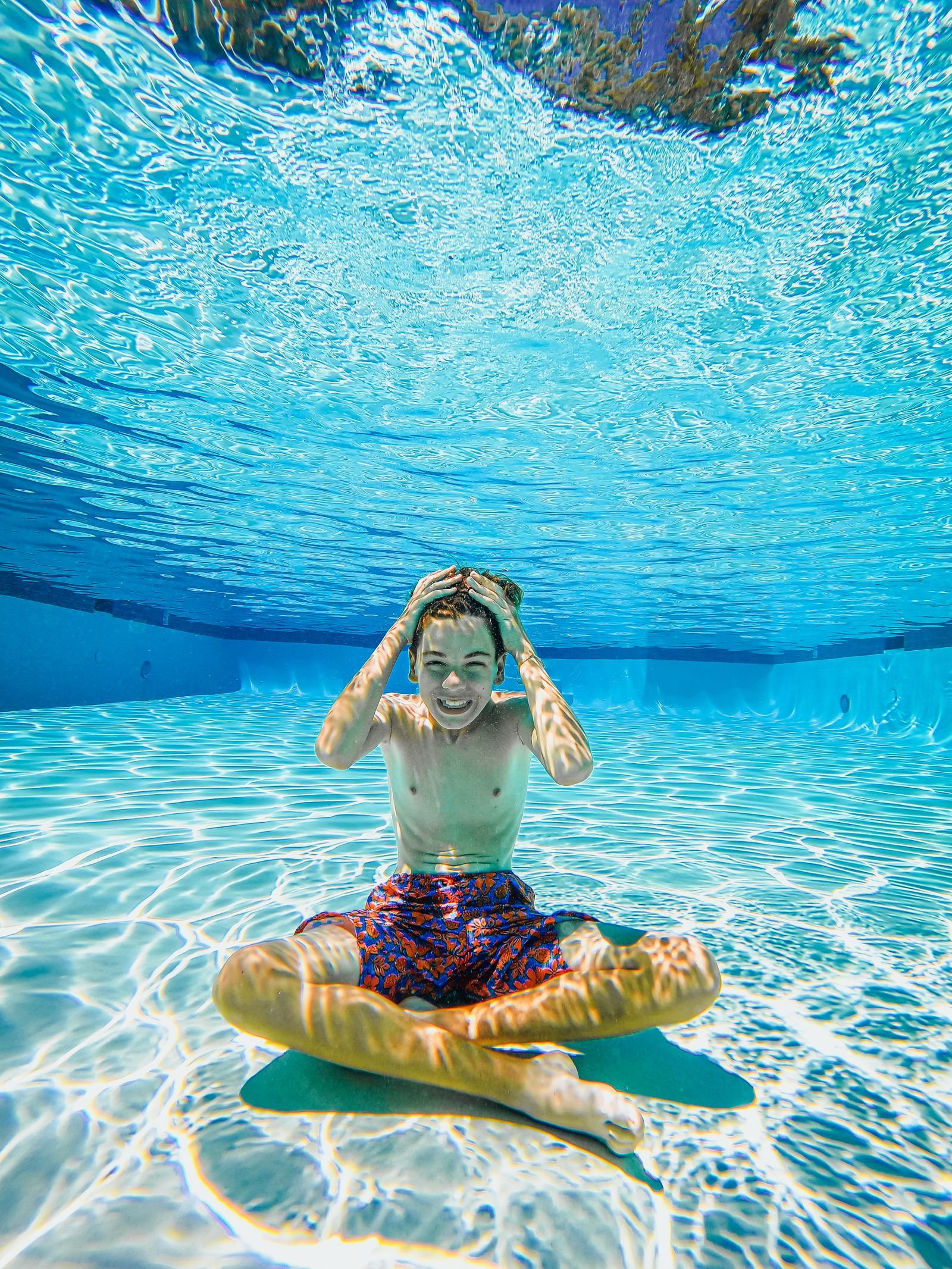 Lachend kind zwemt onder water in een helder zwembad tijdens een dagje zwemmen