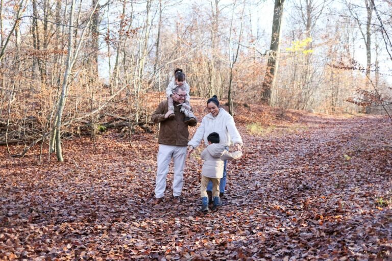 Gelukkig gezin wandelt door zonnig herfstbos — kortingen vergelijken Landal HEMA Center Parcs