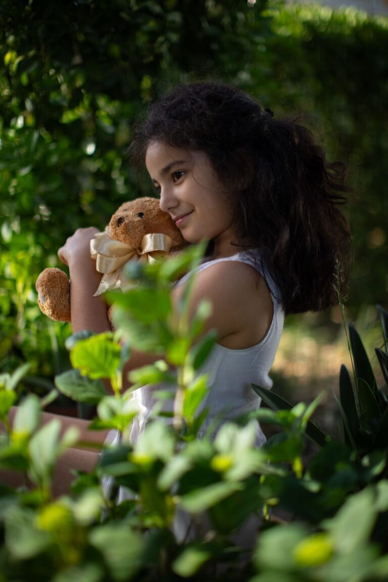 Lachend kind knuffelt een pluche knuffel in een groene tuin, net als de Orry knuffel van Center Parcs