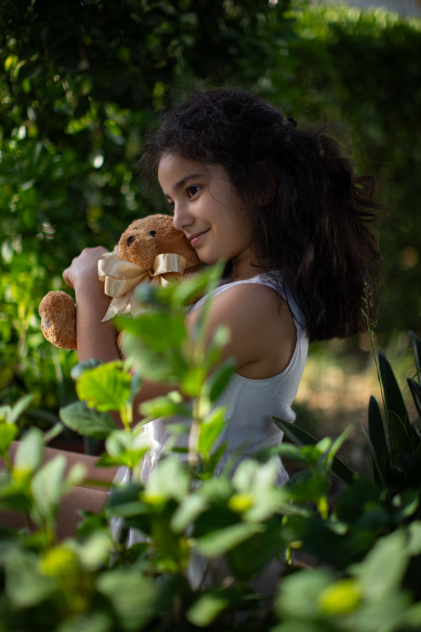 Lachend kind knuffelt een pluche knuffel in een groene tuin, net als de Orry knuffel van Center Parcs