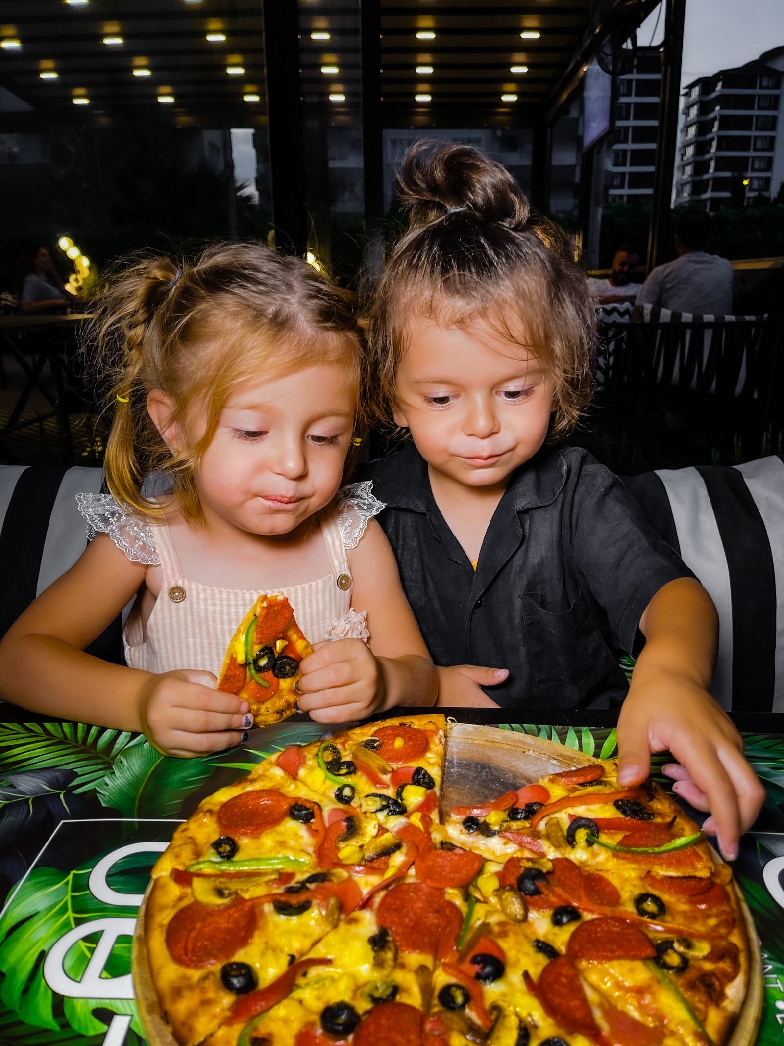 Twee kinderen eten samen pizza in een gezellig restaurant