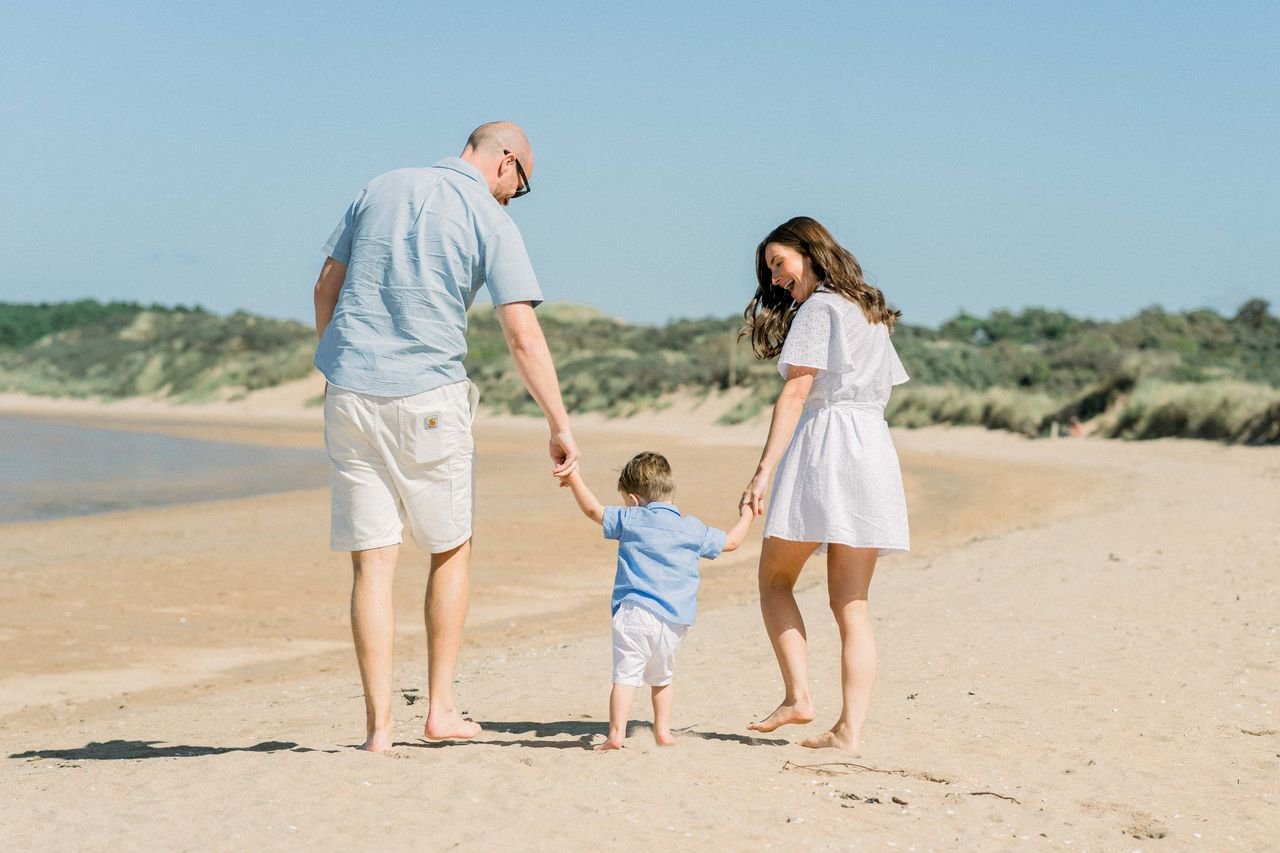 Gezin wandelt hand in hand over het zonnige strand bij Dishoek in Zeeland