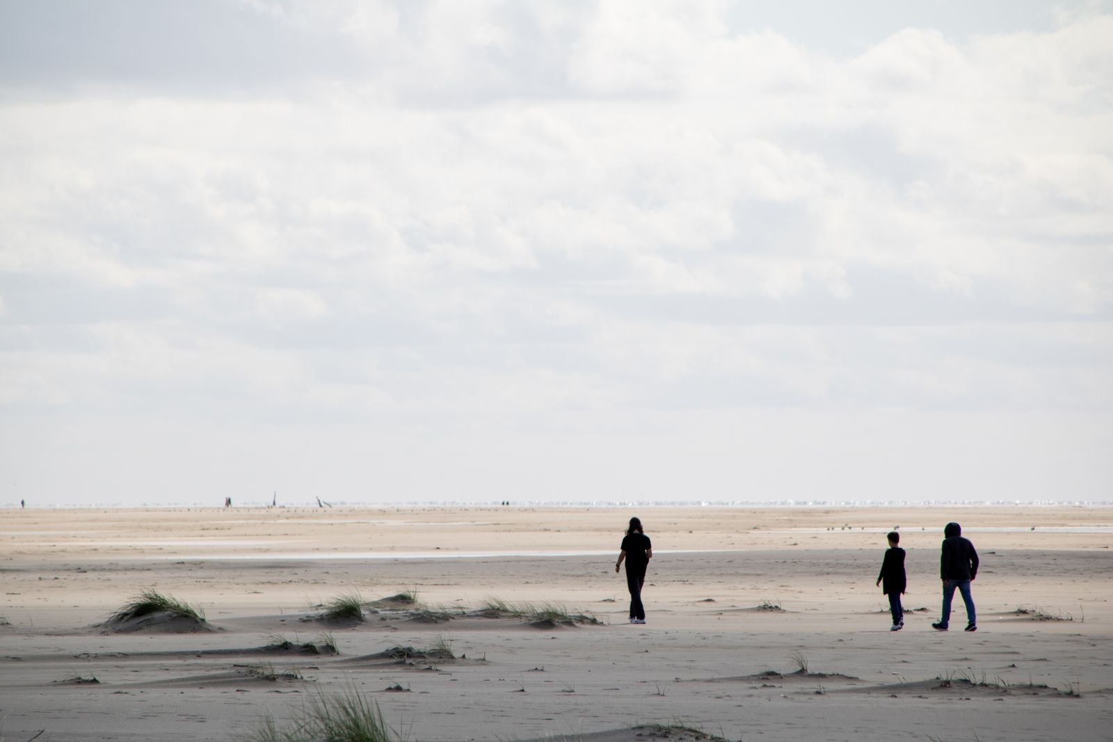 Gezin wandelt over het strand aan de Noordzee bij een vakantiepark aan de Belgische kust