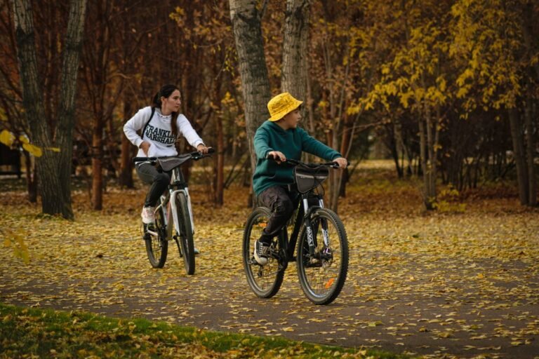 Ouder en kind fietsen door een herfstbos, een van de activiteiten bij Sunparks Mol