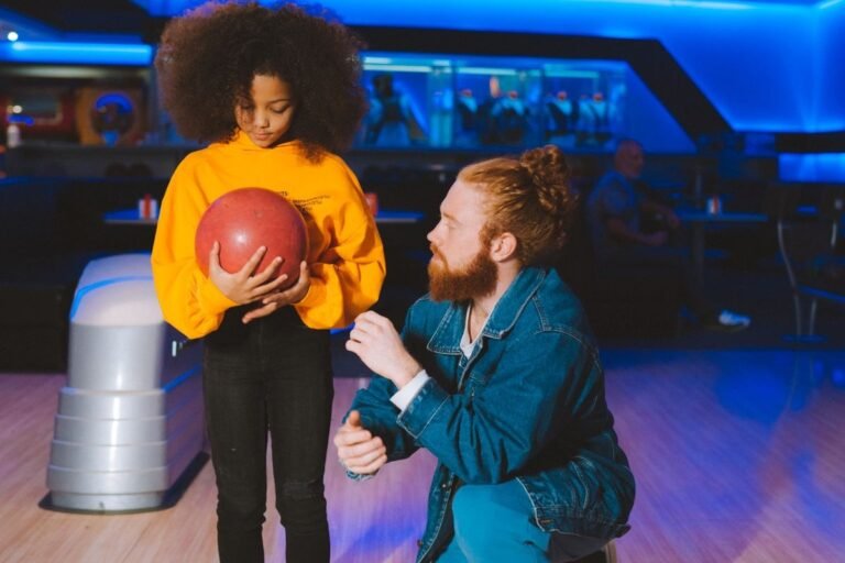 Vader helpt dochter met bowlingbal op indoor bowlingbaan