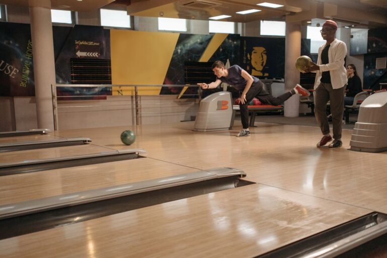 Twee mensen gooien een bal op een indoor bowlingbaan