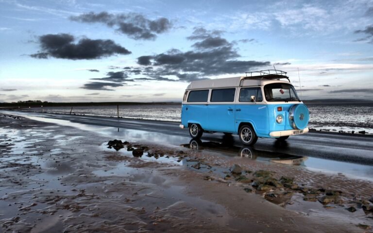 Blauwe camper aan de Noordzeekust bij avondlicht