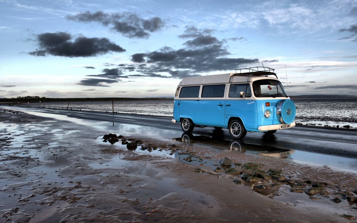 Blauwe camper aan de Noordzeekust bij avondlicht