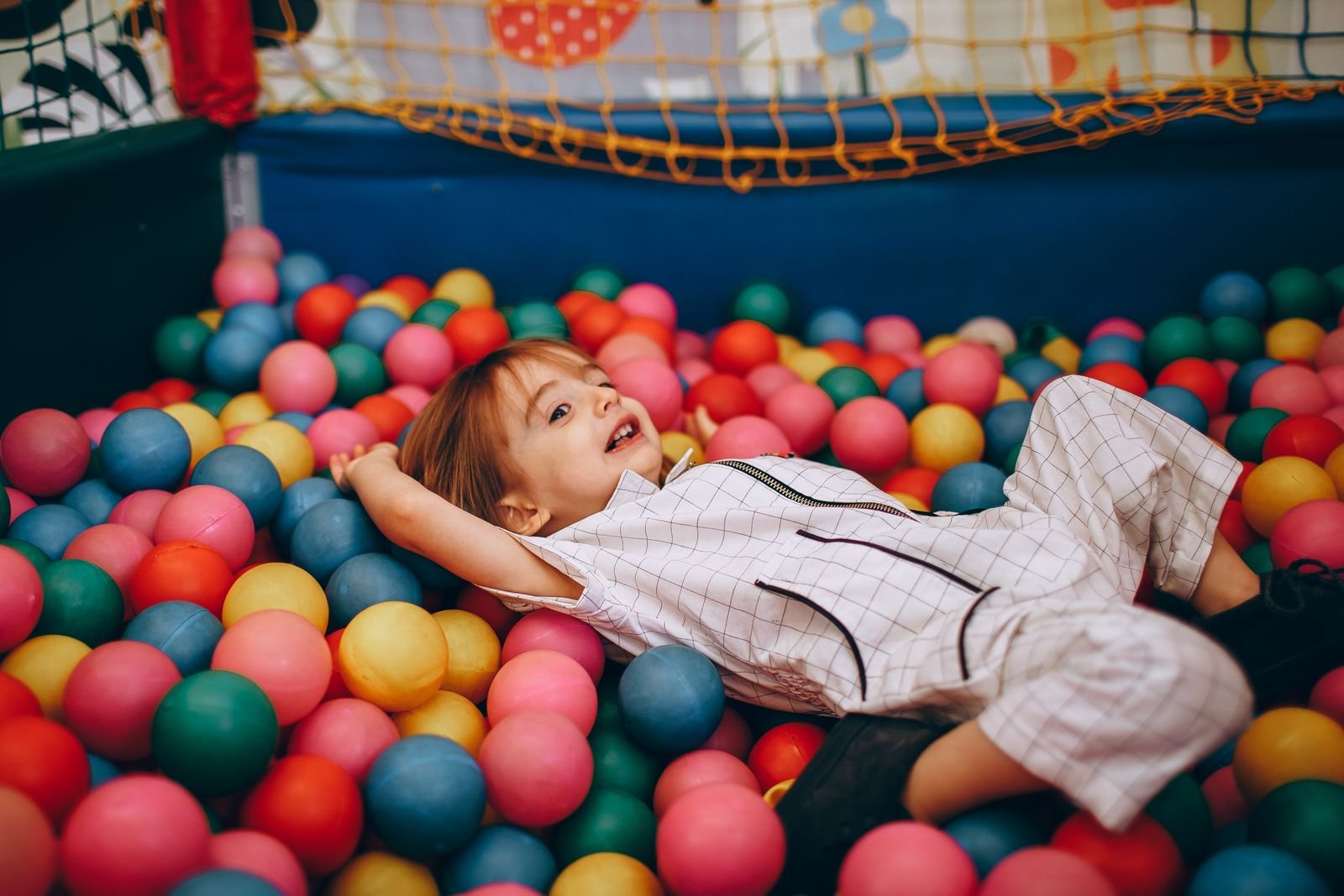 Lachend kind speelt in een kleurrijke indoor speeltuin met ballenbak