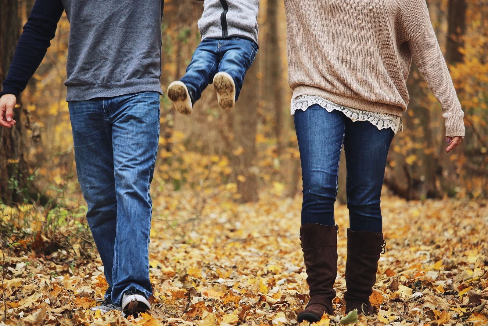 Ouders wandelen met hun kind door een herfstbos, sfeerbeeld bij de Prénatal Center Parcs korting