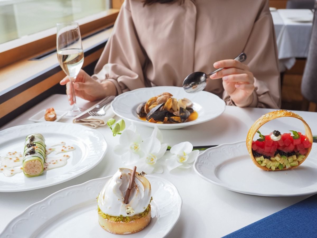 Verschillende gerechten en een glas wijn op tafel in een restaurant met uitzicht