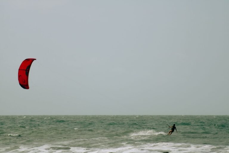 Kitesurfer met rode vlieger op het water bij Center Parcs Port Zélande