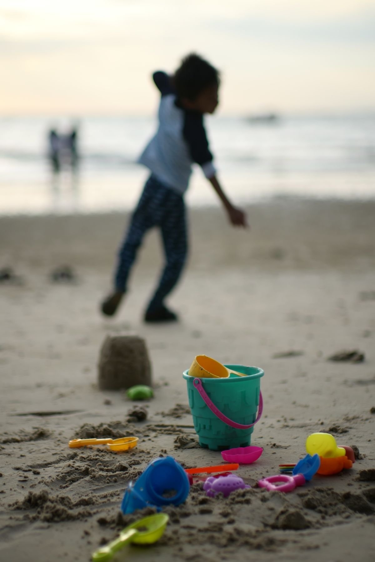 Kind speelt met strandspeelgoed en emmer op het strand bij Roompot Beach Resort Kamperland