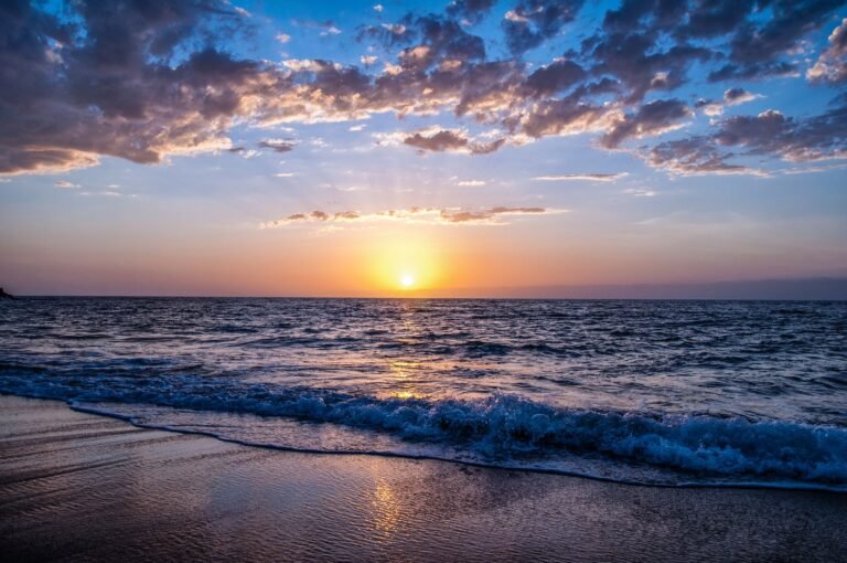 Noordzeestrand bij zonsondergang met golven