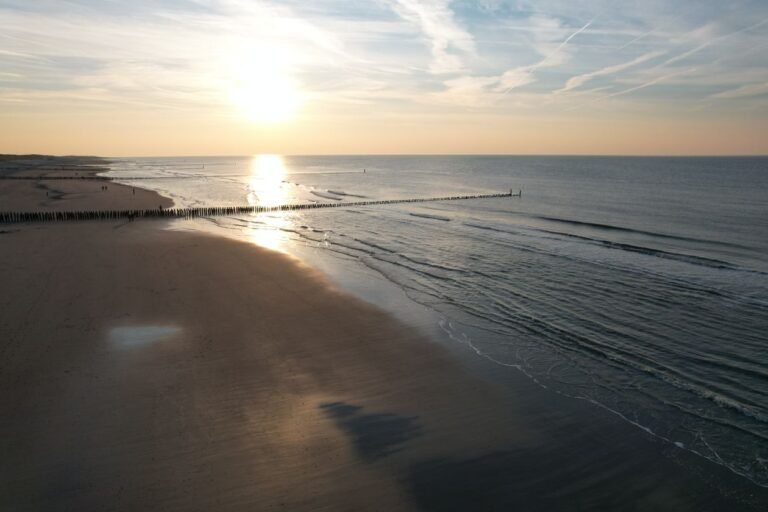 Zonsondergang boven het Noordzeestrand met paalhoofden bij Nieuwvliet in Zeeland