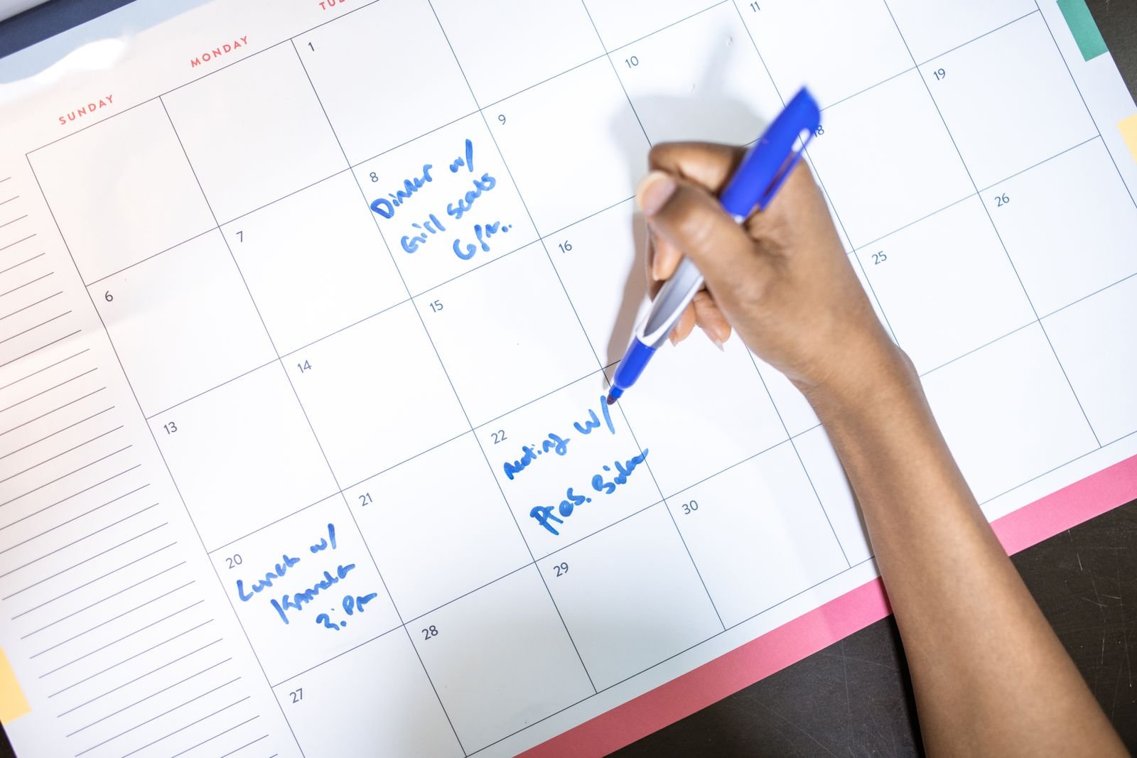 Iemand noteert afspraken op een maandkalender
