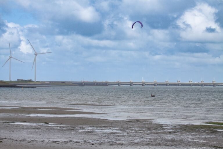 Strand van Kamperland met kitesurfer en windmolens, bij de vraag welk Roompot park het leukst is